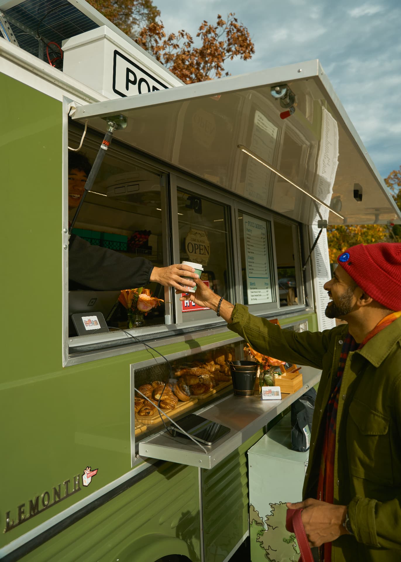 A barista handing a coffee through the trailer window